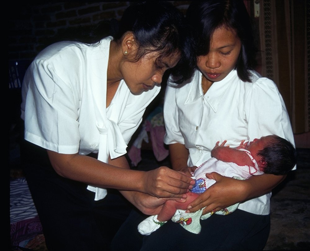 Health worker immunizing infant with Uniject; mother holding infant.