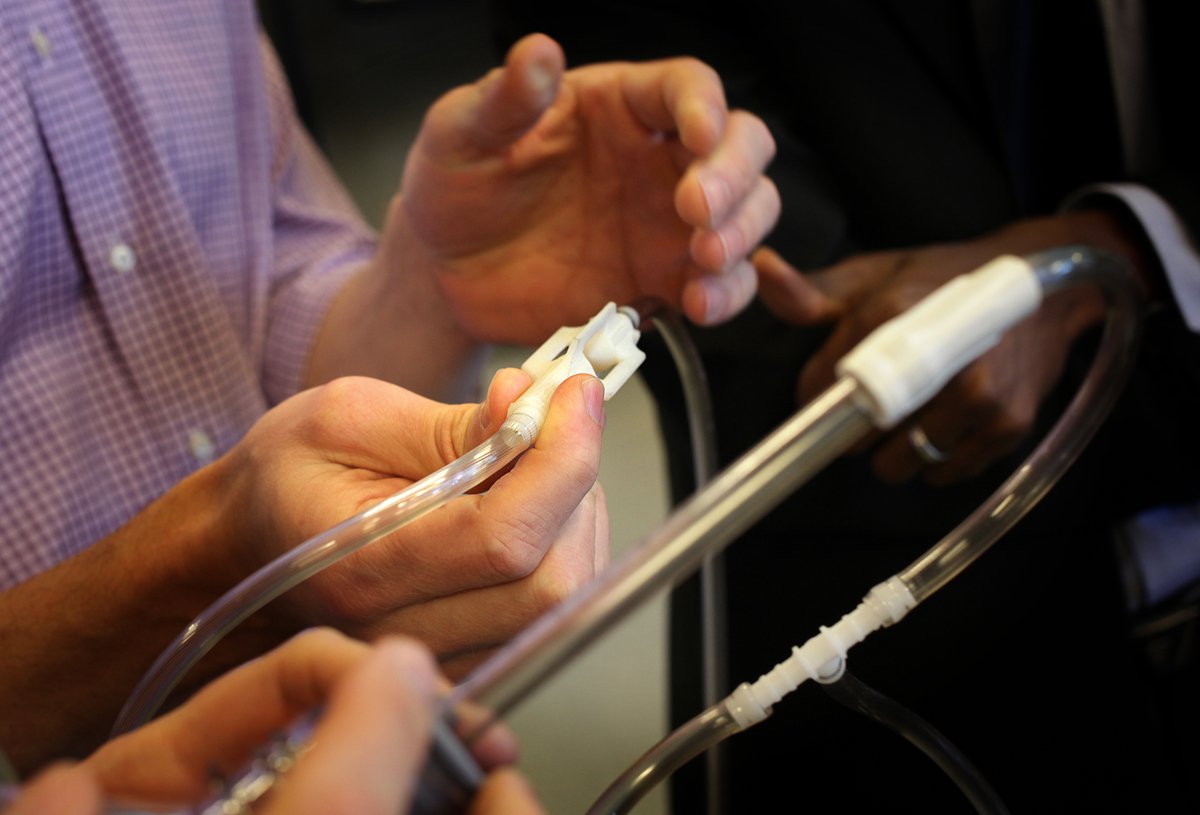 Tubing and 3D-printed device held in hands.