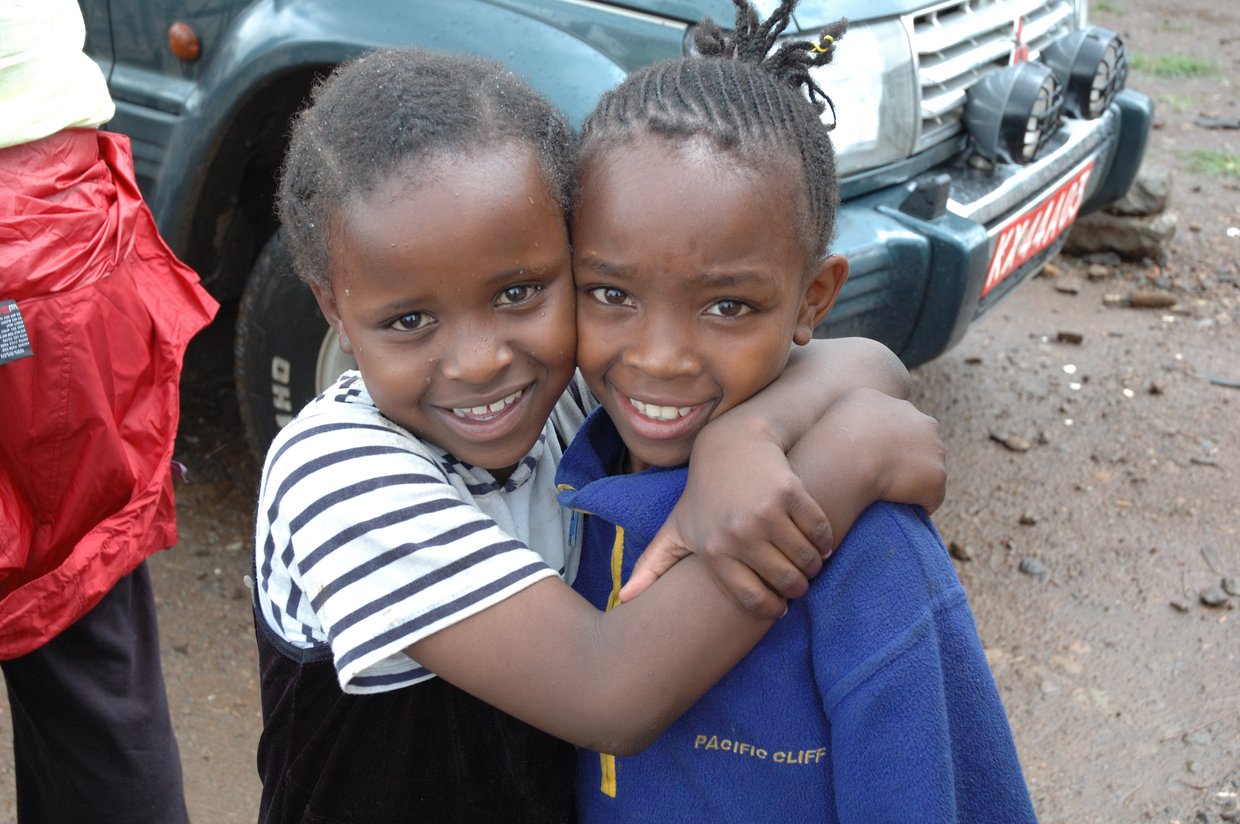 Two girls hugging, smiling at camera.