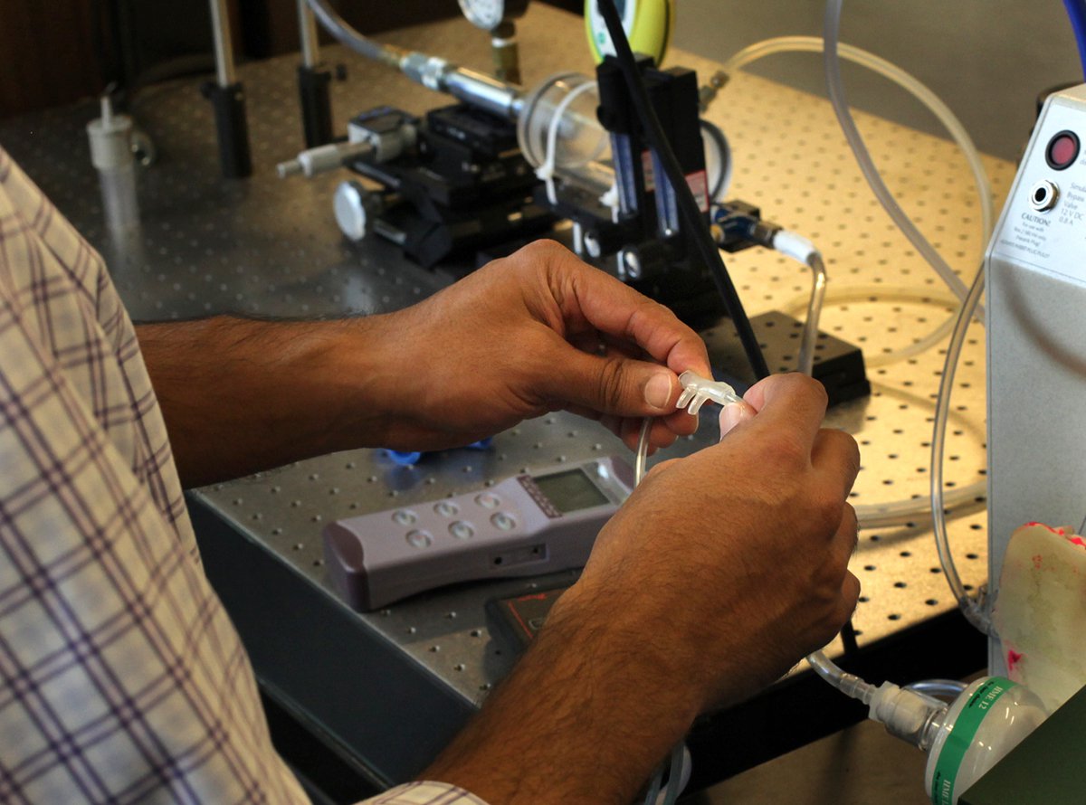 Hands hold tubing designed to be inserted into infant nostrils.