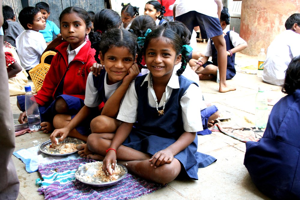 Girls eating rice from a plate.
