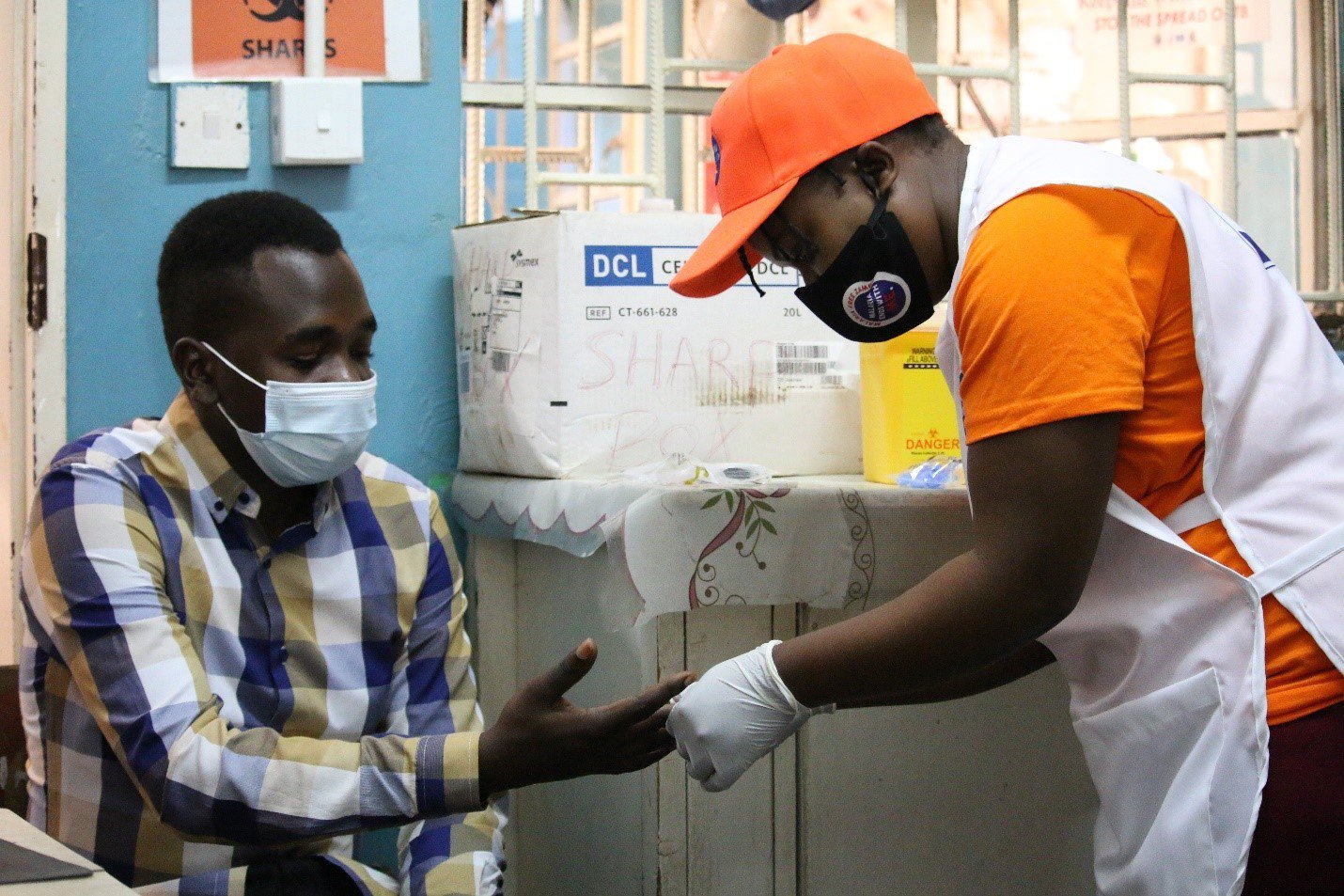 Community health worker Bernadette Chilufya (right) conducts a routine diagnostic test on patient Christopher Chewe at Nakambala Health Facility in Mazabuka, Zambia, during malaria case investigation trainings. Photo: PATH/Chilowekwa Shike.