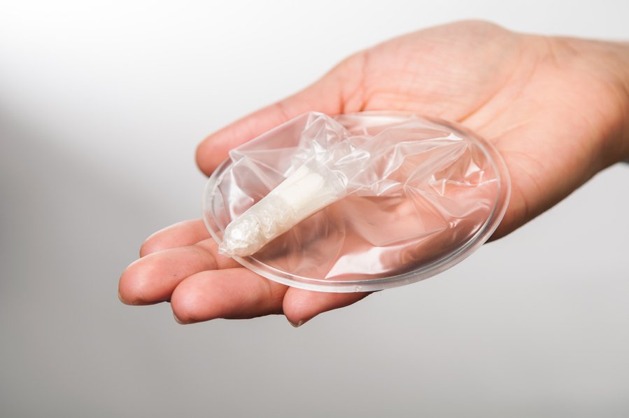 Woman's hand holding the Woman's Condom.