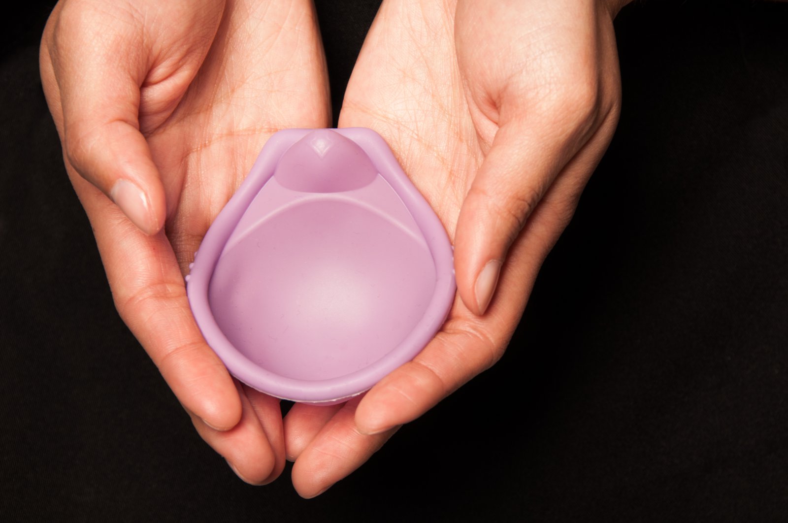 A woman's hands holding a SILCS diaphragm.