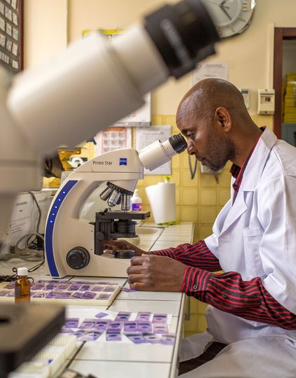 Arthur Dani Hzizidi examines slides for malaria parasites at the Institut National de Recherche Biologique (INRB) in DRC. With PATH/MalariaCARE support, the INRB is helping to build a national archive of malaria slides. Photo: PATH/Georgina Goodwin.