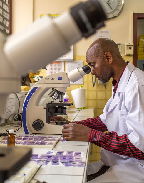 Arthur Dani Hzizidi examines slides for malaria parasites at the Institut National de Recherche Biologique (INRB) in DRC. With PATH/MalariaCARE support, the INRB is helping to build a national archive of malaria slides. Photo: PATH/Georgina Goodwin.