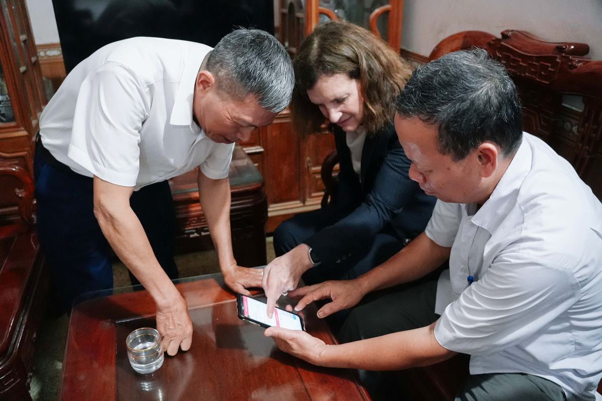 4. A commune health worker guides a patient with hypertension to update their blood pressure on the Sức Sống Mới application during a home visit.