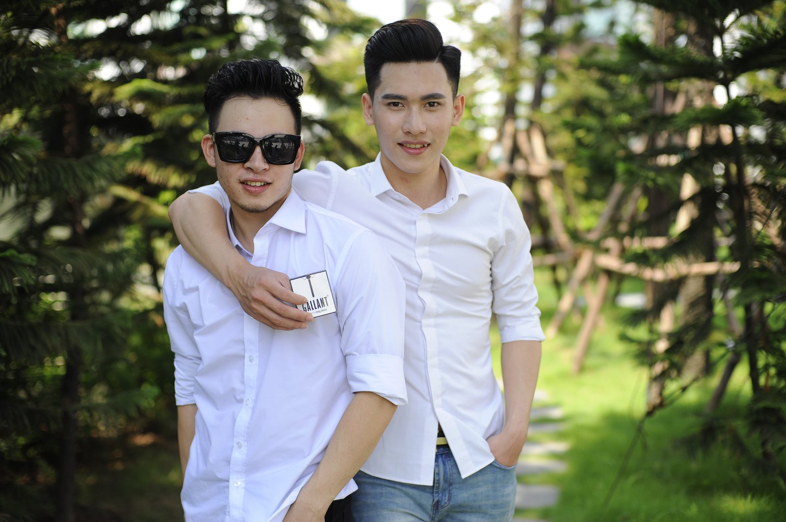 Two young men, one with his arm around the other, holding a condom package.