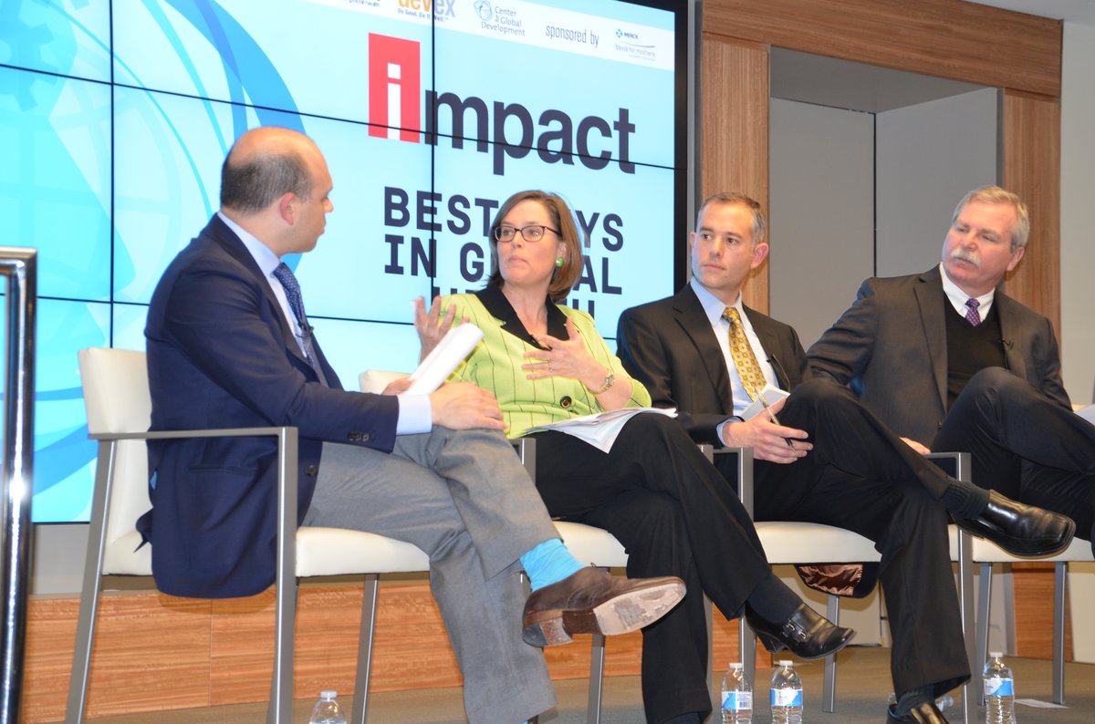 Woman seated on stage with three men speaks.