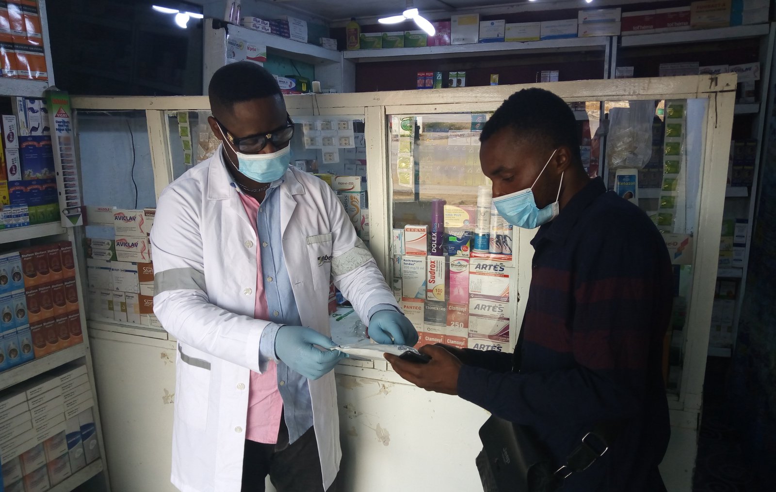 Dr. Ali Kitoko provides information to an interested customer on an HIV self-test at Pharmacie Binamet in Lubumbashi, Haut-Katanga. PATH/Raphael Mwamba.