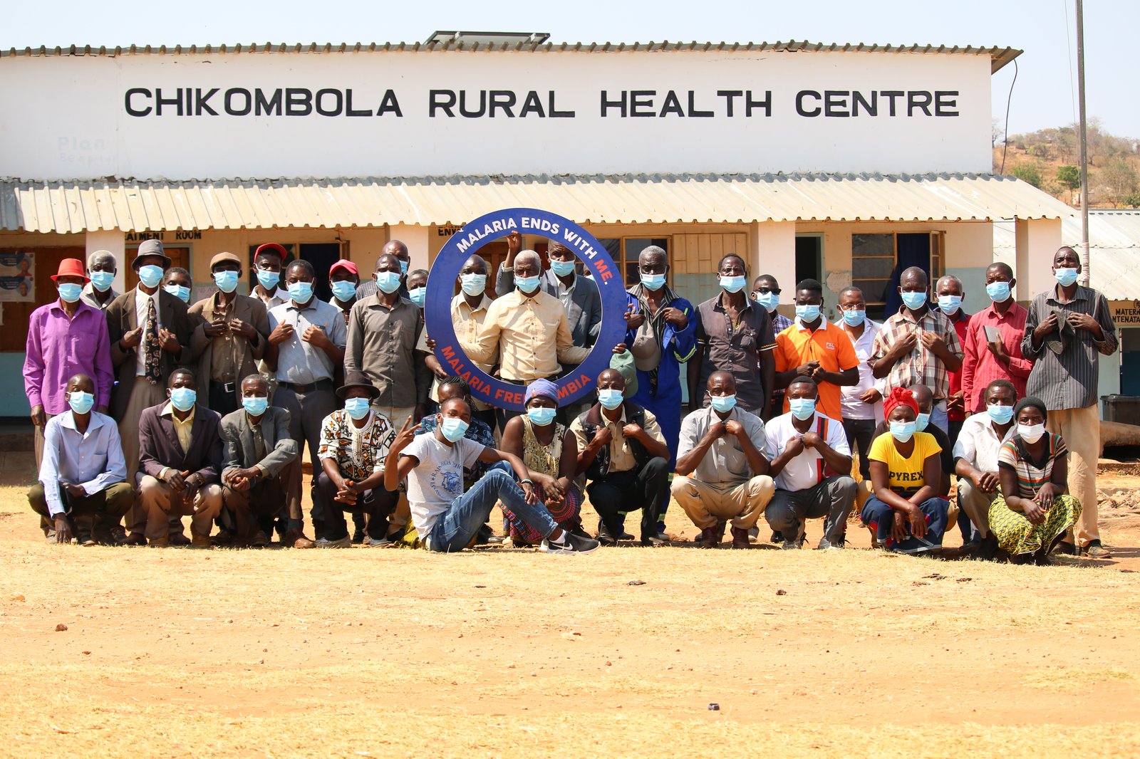 Community leaders and members, neighborhood health committee members, health facility staff, and community health workers from Chikombola Rural Health Centre pose for a photo after a community engagement meeting. Photo: PATH/Emma Lwando.