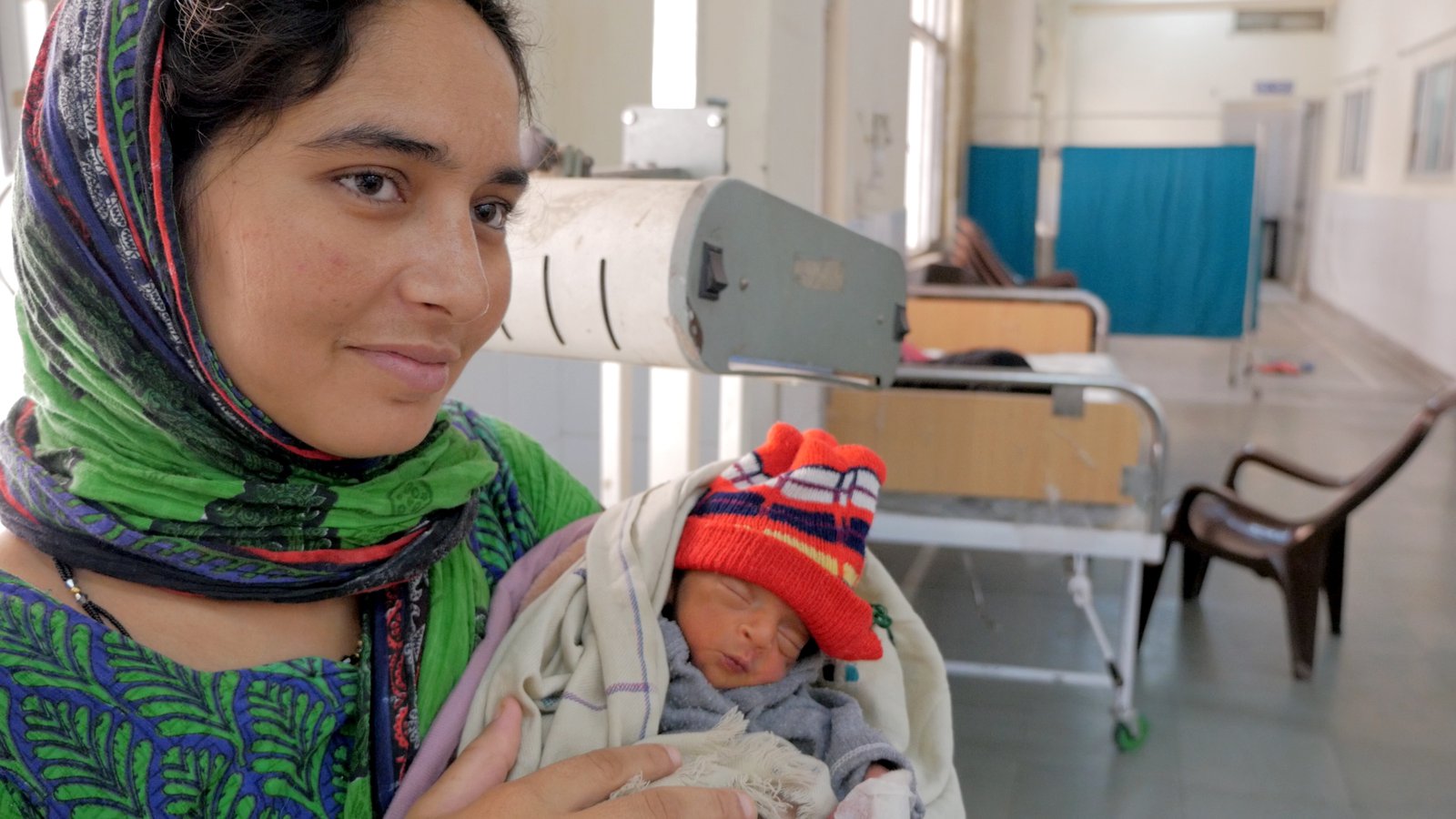 A woman holds a preterm newborn baby.