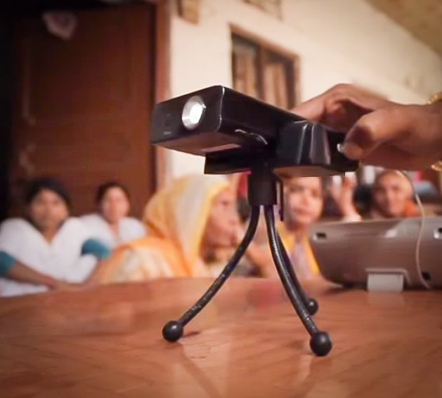 Tiny video projector is adjusted by a woman's hand.