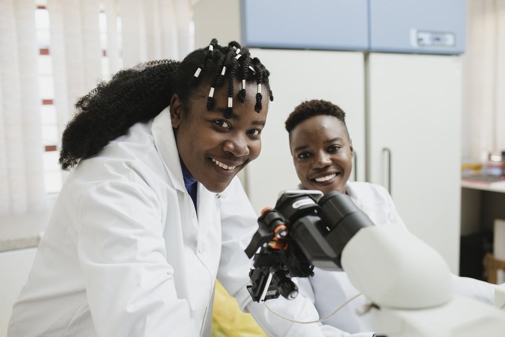 At the National Malaria Elimination Centre in Lusaka, Zambia, Mulenga Mwenda-Chimfwembe (Laboratory Scientist) and Tricia Hibwato (Project Assistant) examine malaria blood slides using the AIScope software. It is hoped that this software will allow faster