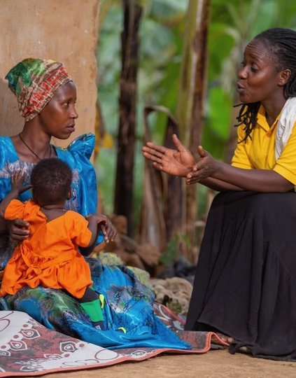 A member of a village health team (right) checks the immunization status of a child during a home visit in Southwestern Uganda. Village health teams play a critical role in reaching remote communities with lifesaving vaccines. Photo: PATH.