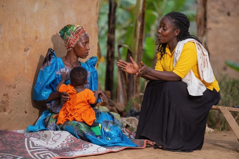 A member of a village health team (right) checks the immunization status of a child during a home visit in Southwestern Uganda. Village health teams play a critical role in reaching remote communities with lifesaving vaccines. Photo: PATH.