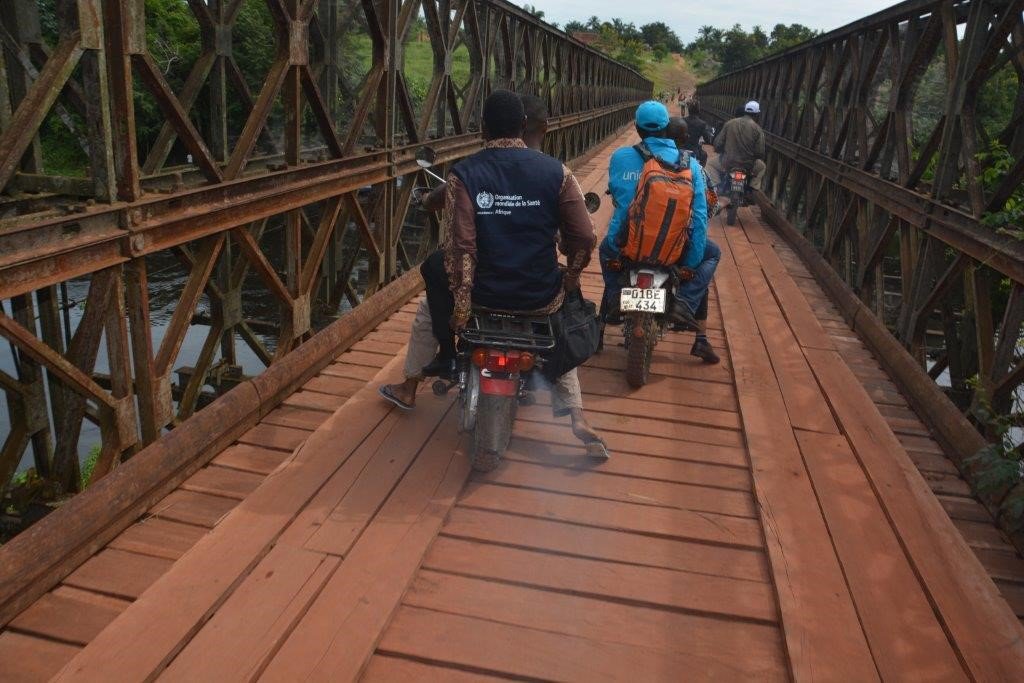 A group of motorcyclists travel across a bridge.