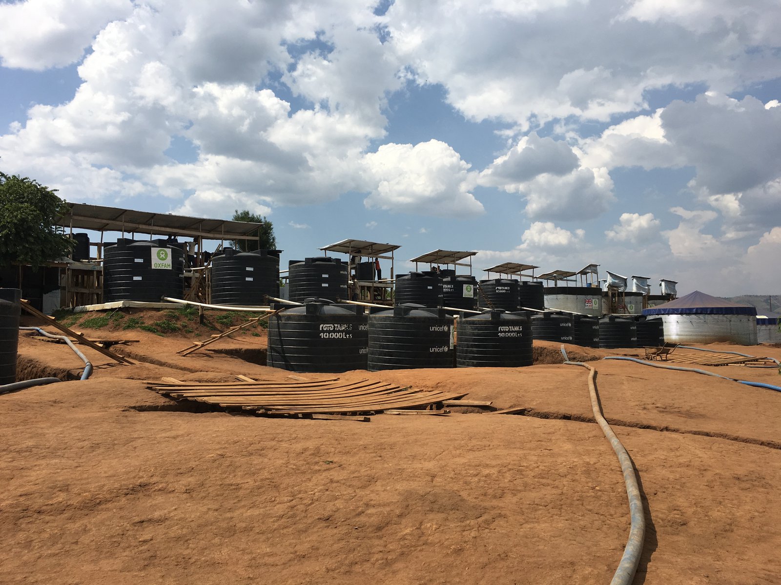 A series of water tanks and cisterns connected by hoses sit on a hillside.