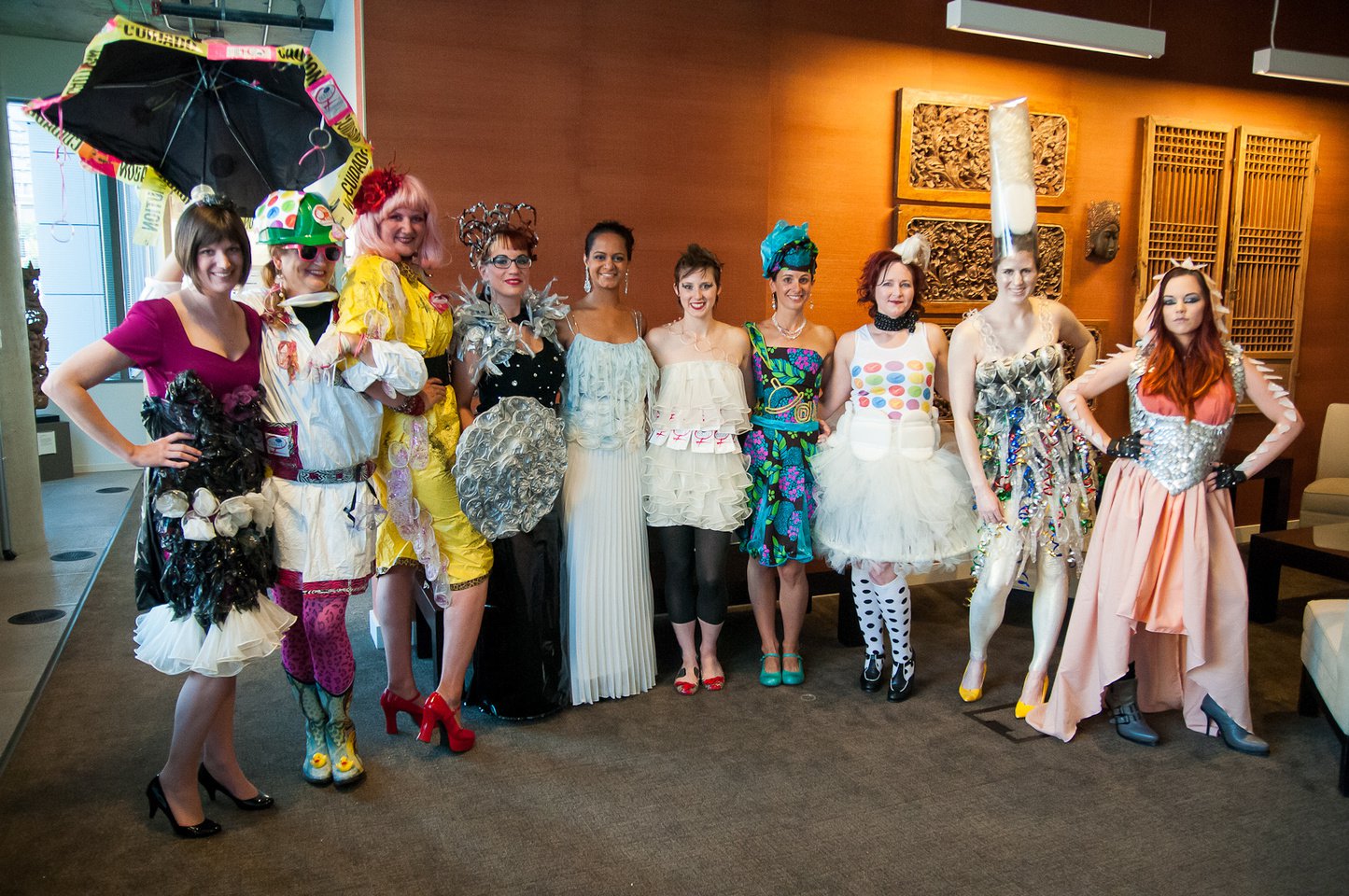 Ten women pose in colorful dresses that incorporate condoms.