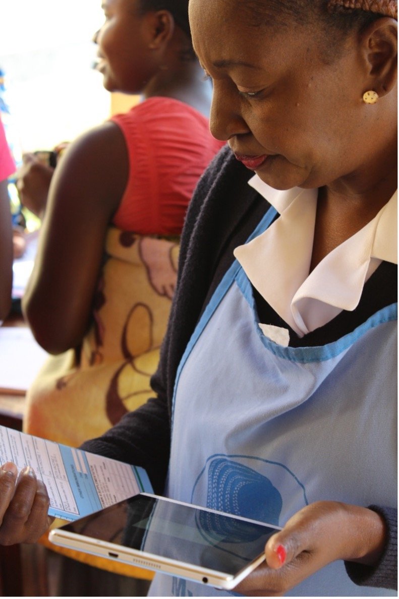 A health care worker reviews a patient registration form before entering patient data into the Tanzania Immunization Registry on her tablet. Photo: PATH/Trevor Snapp.