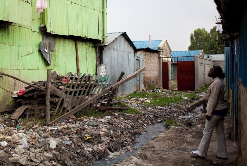 A women stands in front of a building and pile of trash