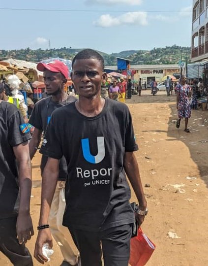 Youth club volunteers speak to market vendors in Kisantu while wearing PATH-issued awareness vests. The volunteers use simple, clear language to explain the vaccine and follow up on missed doses. Credit: UNICEF.