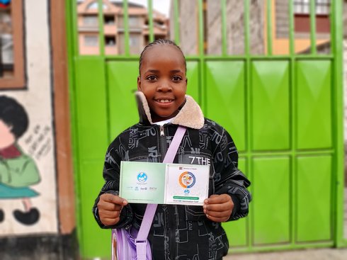 Nine-year-old Joy holds her vaccination card after receiving the typhoid conjugate vaccine. Credit: PATH/Peter Abwao.