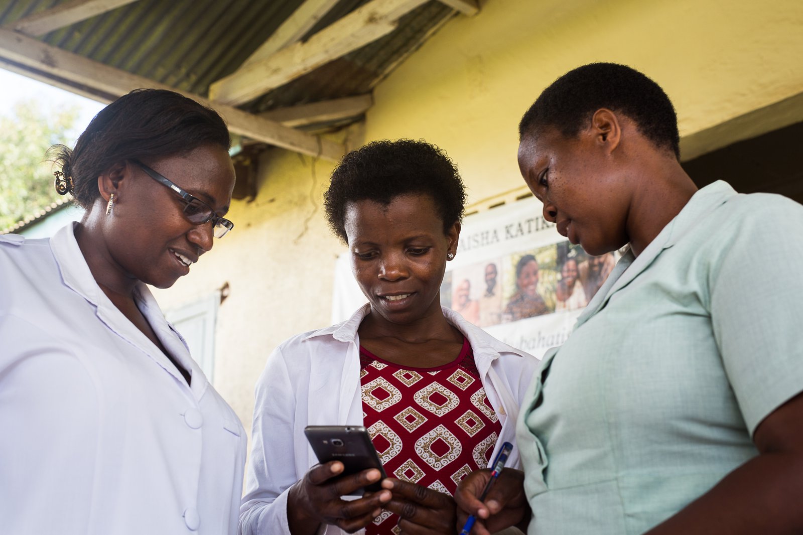 _T9C0325.jpg . Health care workers in Tanzania look at a mobile phone. Photo: PATH/BID project.