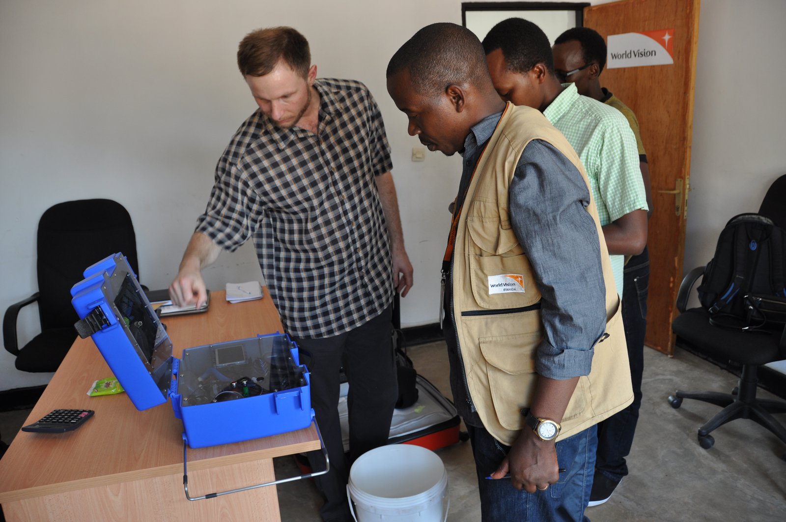 Jesse Schubert leans over a chlorine generator as several men look on.