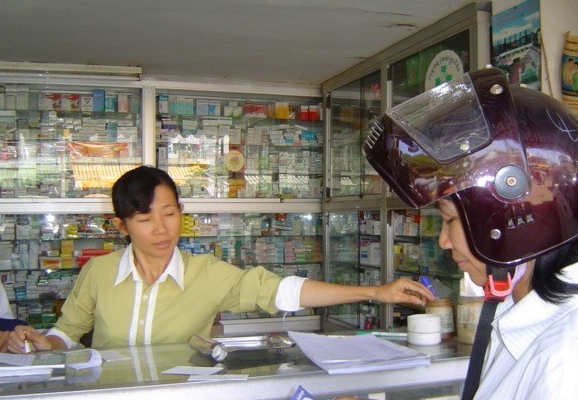 A person wearing a helmet talks to a woman behind a counter.